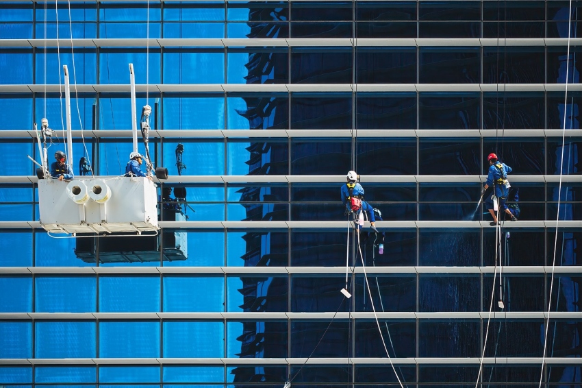 people working at height cleaning windows wearing safety harnesses and lanyards